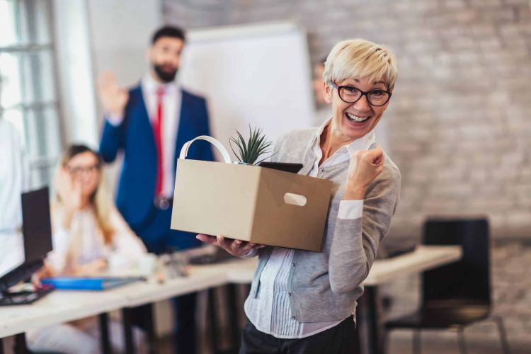 femme employée âgée quittant le bureau avec une boîte